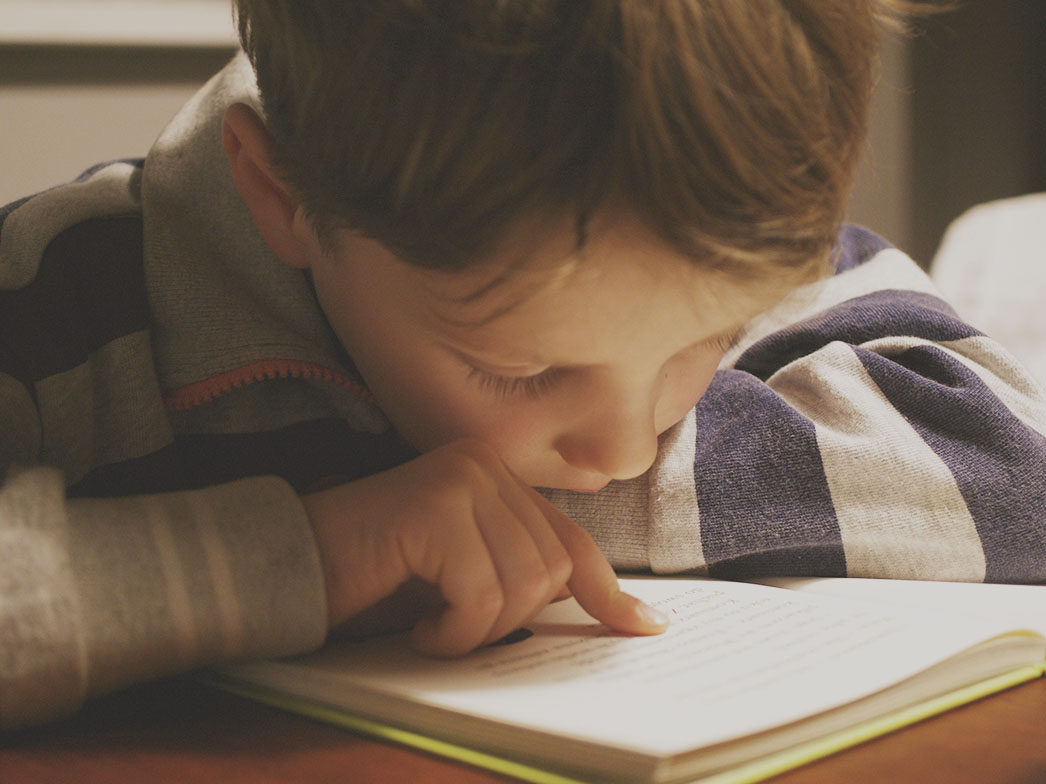 A young child reading an open book with growing confidence